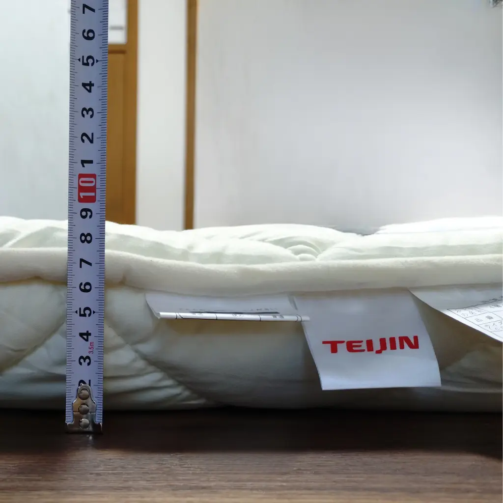 寝姿勢サポート敷布団（極厚タイプ）の厚みをメジャーで測っている写真。実際のボリューム感が分かる。